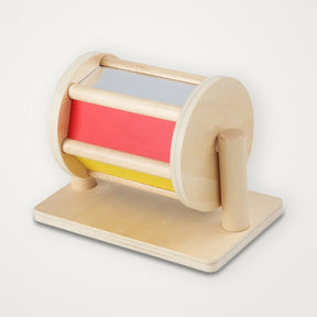Tambor giratório de madeira com painéis vermelho e amarelo e um espelho, preso numa base de madeira